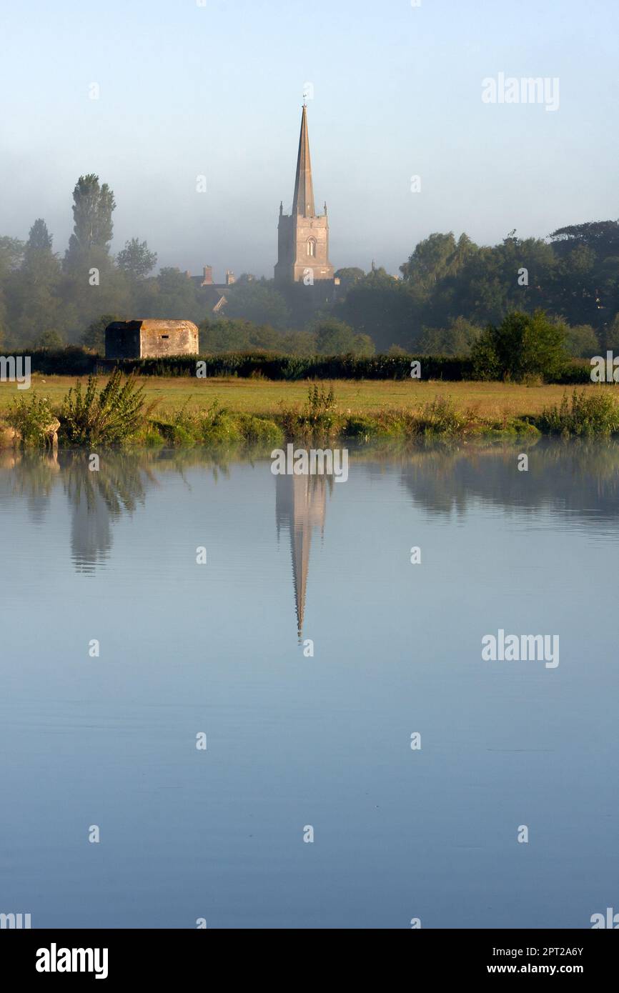 LECHLADE, GLOUCESTERSHIRE, Großbritannien - 04. JULI 2008: Blick über die Themse in Richtung St. Lawrence Kirche in sanftem Morgenlicht mit Reflexion Stockfoto