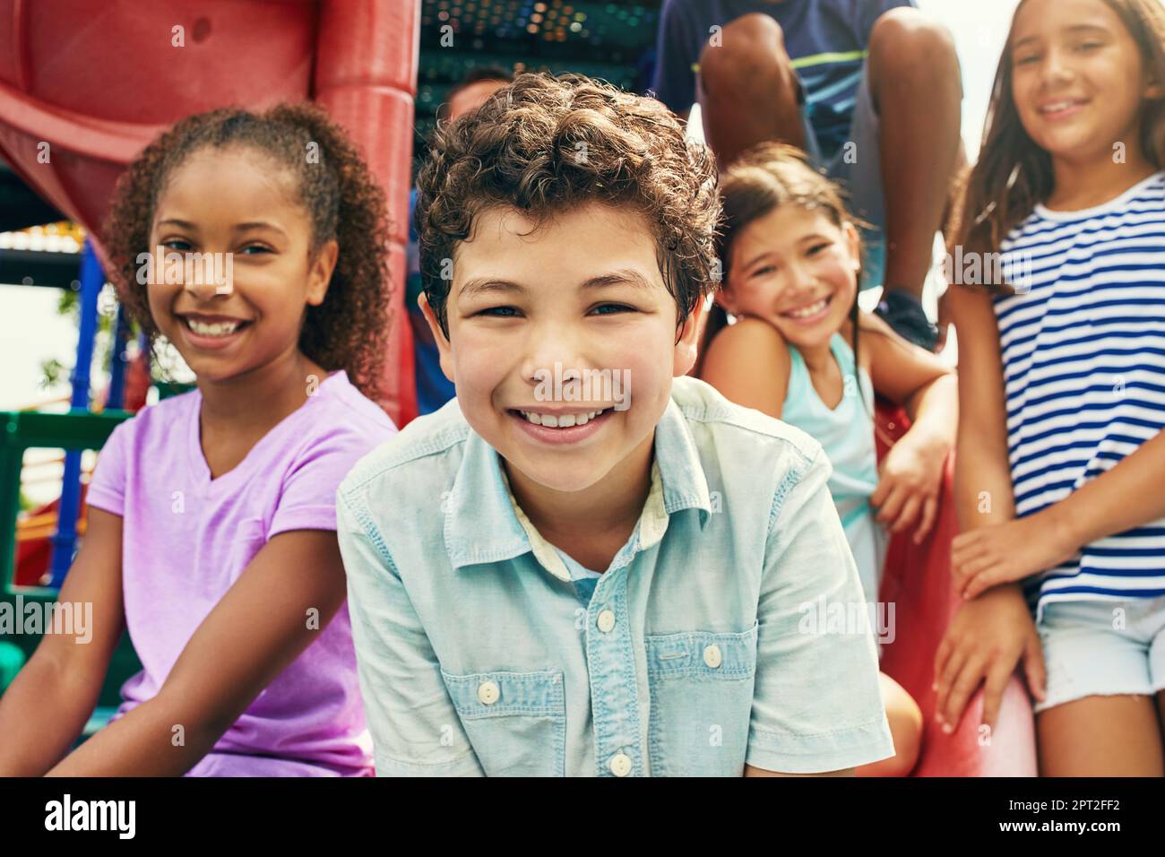 Kilometerlange Lächeln, Freunde um sich zu haben. Eine Gruppe junger Freunde, die zusammen auf einem Spielplatz abhängen. Stockfoto