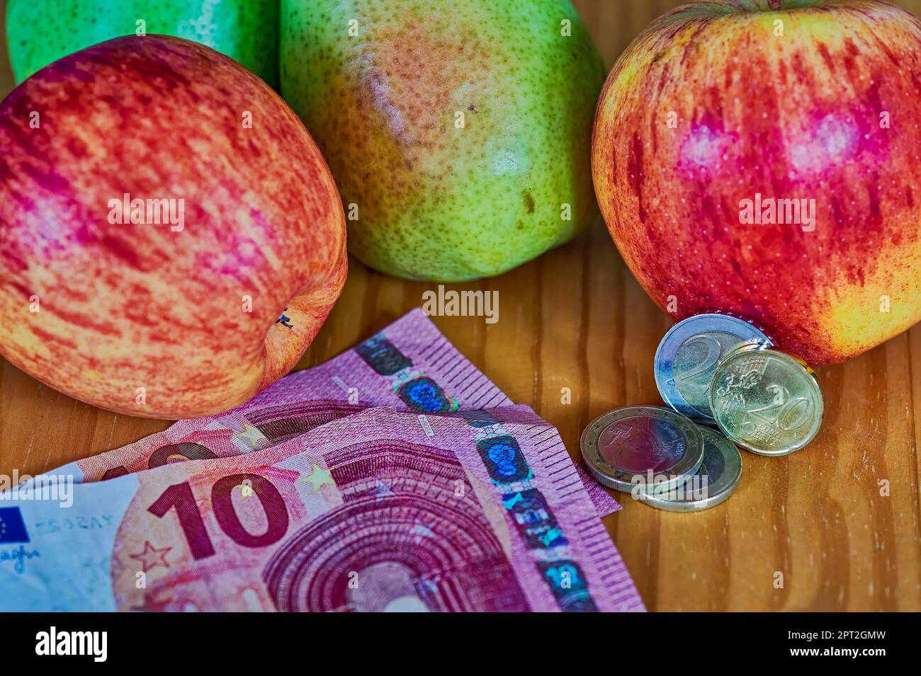 Obst liegt zusammen mit europäischem Geld auf einem hölzernen Hintergrund. Stockfoto