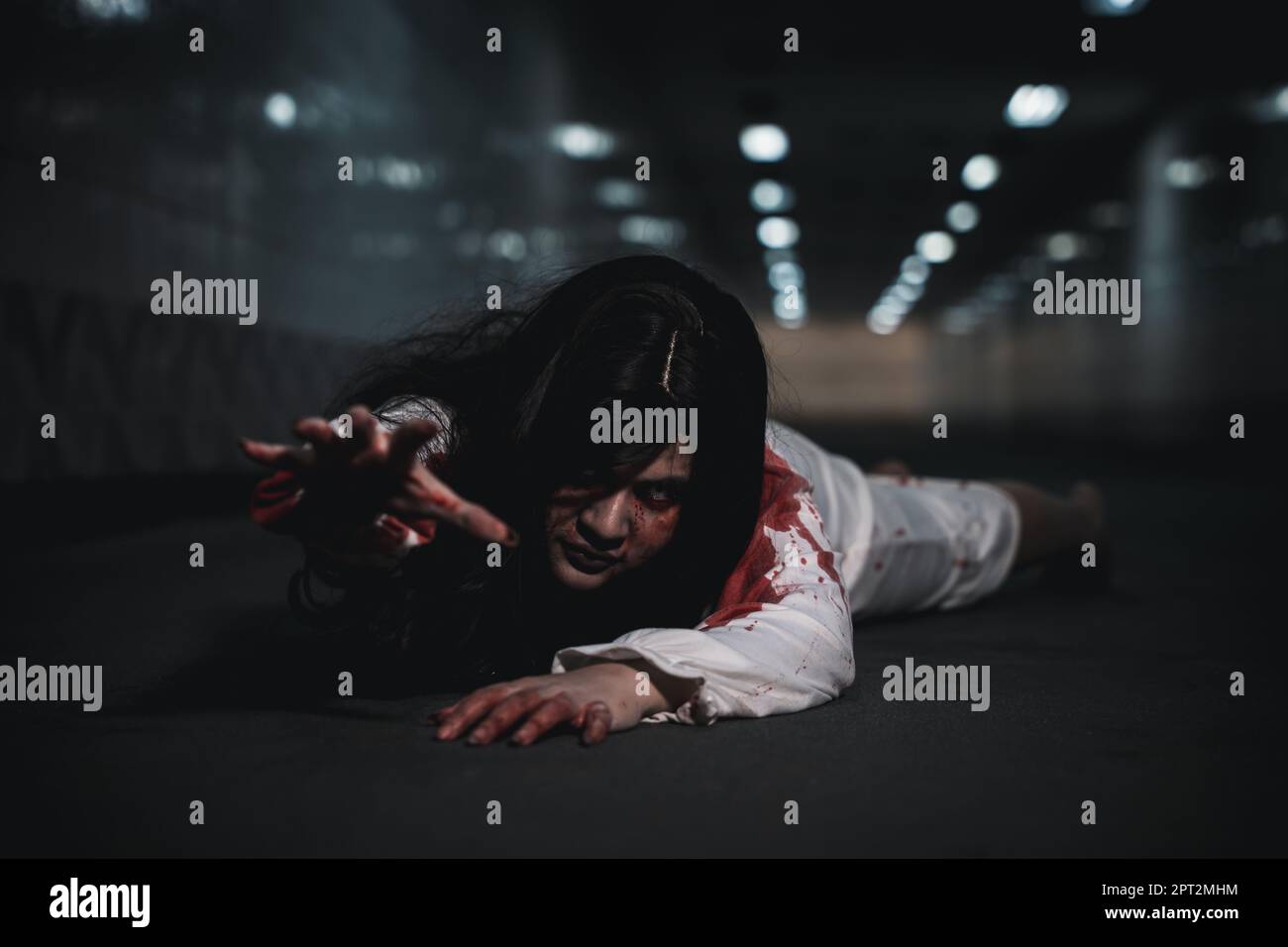 Halloween Tag Horror Konzept. Asiatische Frau Zombie mit Blut gruselig kriechen bewegen langsam kriechen aus, gruselige Geist zerzauste Haare bedeckt ihr Gesicht mit Stockfoto