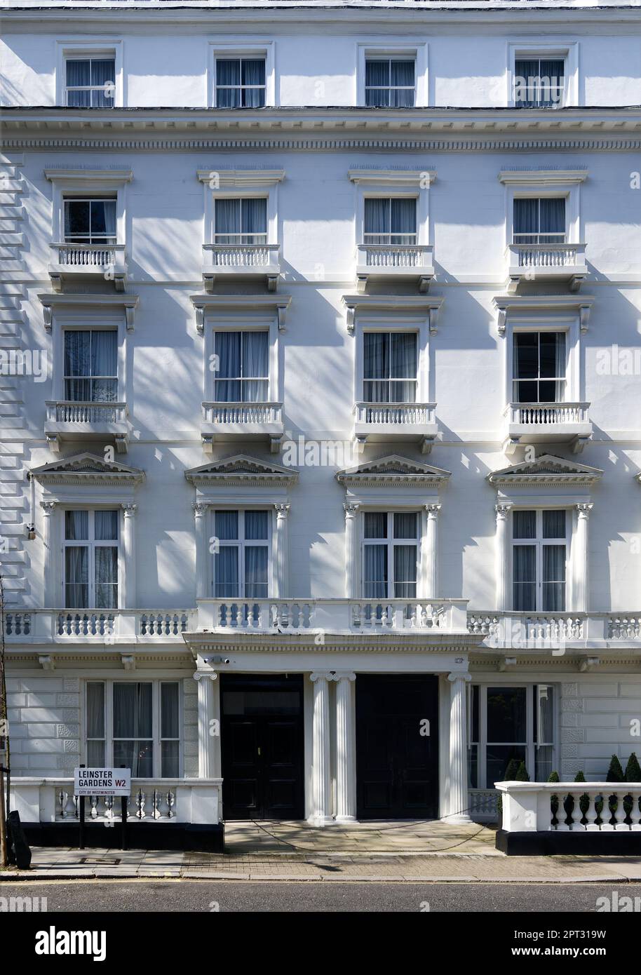 Reihen von Fenstern und Balkonen auf einer traditionellen, weiß bemalten Wohnterrasse in Bayswater, London, England Stockfoto