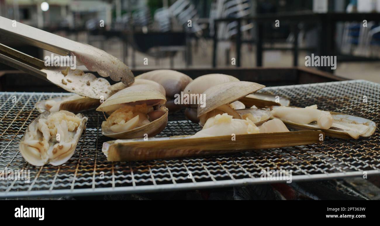 Frische, kurzhalsige Muschel und Razor Clam auf dem Grillnetz Stockfoto