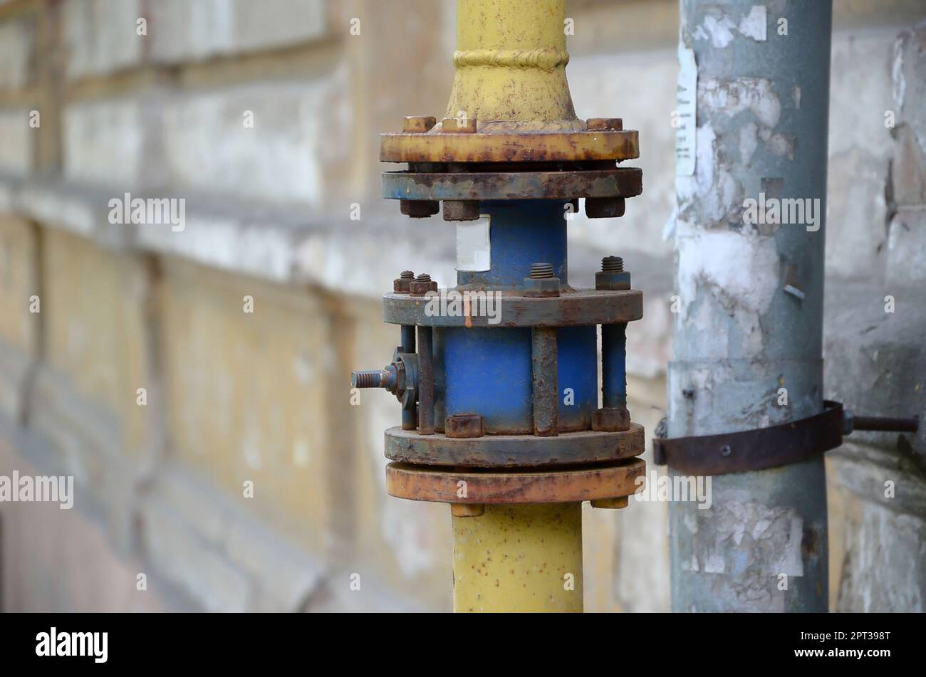 Gelbe Gasleitung vor Wohnhaus an der Wand. Stein Wand Textur Hintergrund natürliche Farbe. Stockfoto