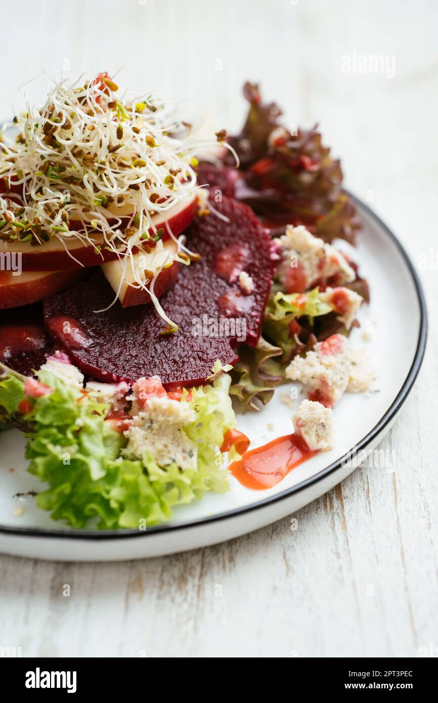 Rüben- und Apfelsalat auf gemischtem Grün mit Erdbeer-Vinaigrette Stockfoto