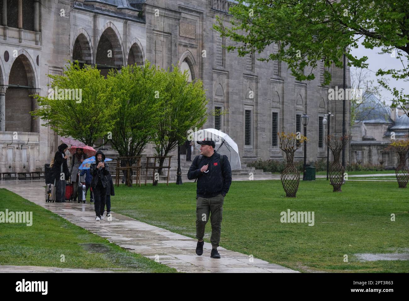 Istanbul, Türkei. 27. April 2023. Ein Mann hält einen Schirm, um ihn vor dem Regen im Garten der Süleymaniye-Moschee zu schützen. Trotz des regnerischen und bewölkten Wetters zog die Dichte der Touristen im Stadtteil Süleymaniye von Istanbul, einer der beliebtesten Städte der Welt, Aufmerksamkeit auf sich. (Foto: Mine TOZ/SOPA Images/Sipa USA) Guthaben: SIPA USA/Alamy Live News Stockfoto