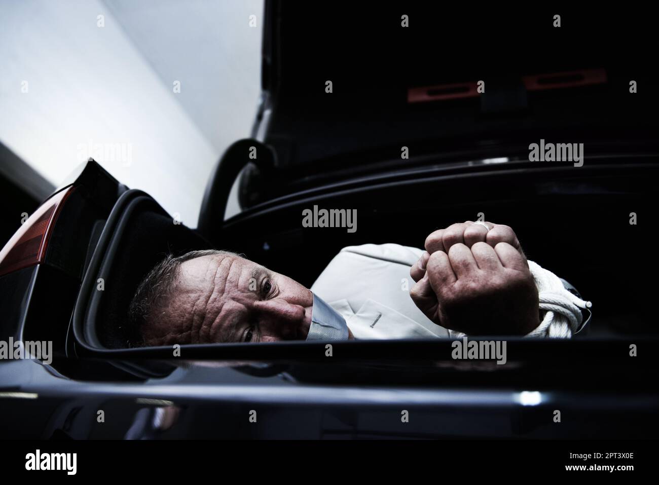Vergeben. Ein ängstlicher Geschäftsmann, gefesselt und geknebelt im Kofferraum seines Autos Stockfoto