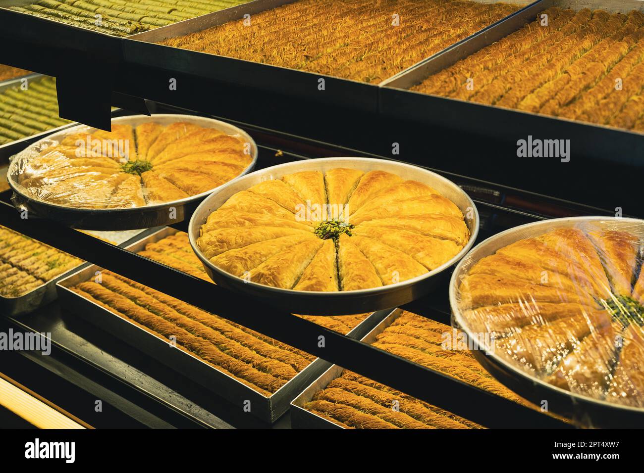 Perspektivische Ansicht Nahaufnahme von großen Platten aus arabischer süßer Baklava oder Baklawa auf den Regalen des Straßenladens Fenster Stockfoto