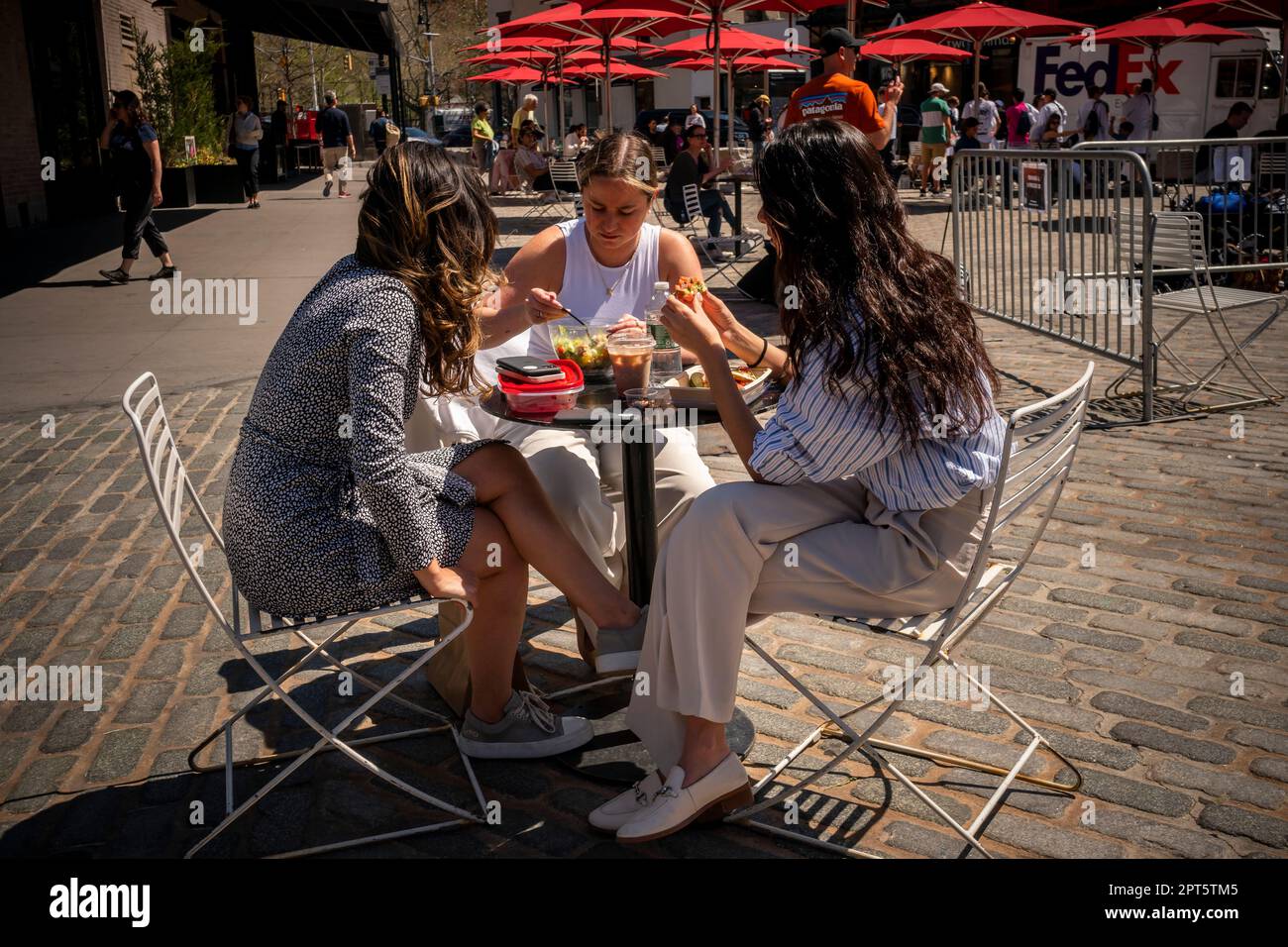 Besucher des Gansevoort Plaza im Meatpacking District in New York nutzen das ungewöhnlich warme Wetter, um im Freien zu Mittag zu essen. Die Temperaturen im Frühling werden voraussichtlich um 80 Grad steigen, sodass der Frühling mehr wie im Juli wirkt. (© Richard B. Levine) Stockfoto