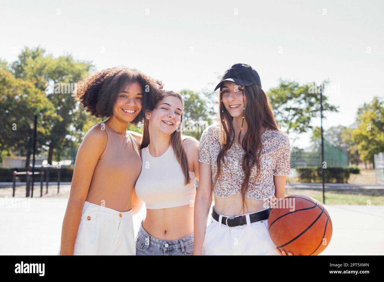 Multikulturelle Gruppe junger Freundinnen, die sich im Freien zusammentun und Spaß haben. Stylische, coole Teenager-Mädchen treffen sich auf dem Basketballplatz, Freunde sind bereit Stockfoto