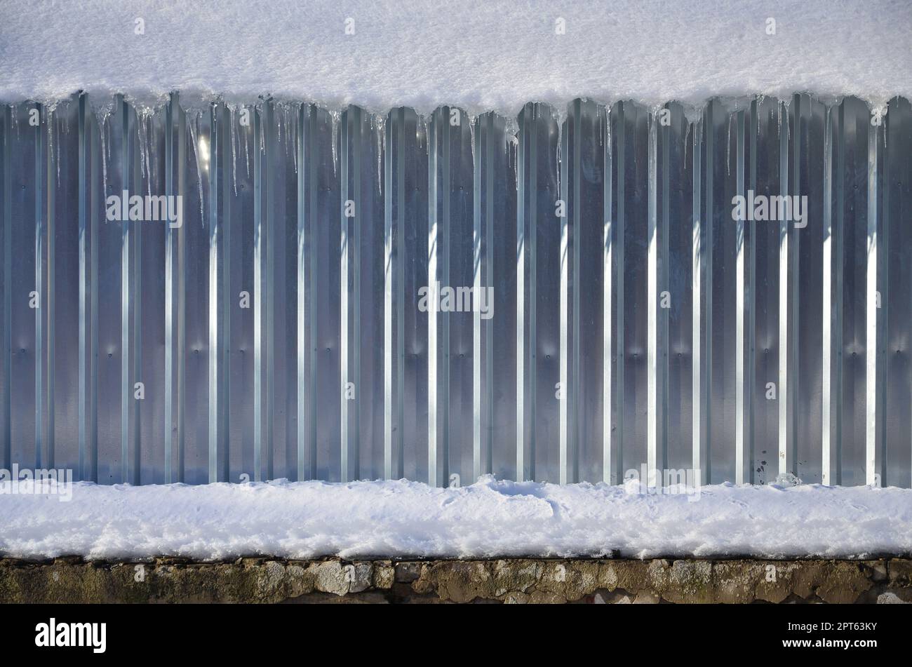 Die Textur von glänzendem Metall und geprägte Wand bei Tageslicht im Winter mit einer dicken Schicht Schnee auf es. Stockfoto