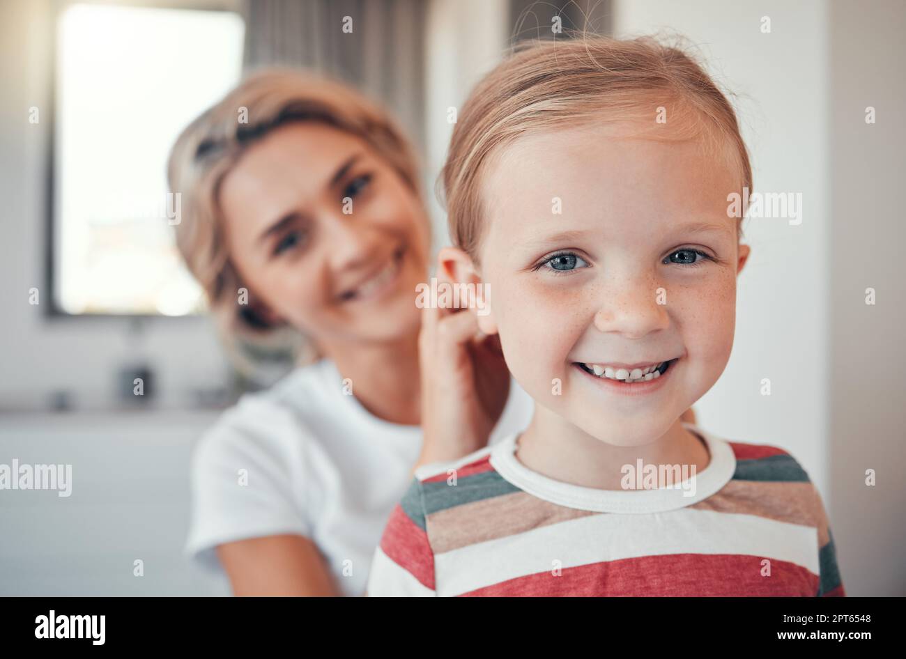 Liebende Mutter, die kleine Töchter gebürstet und ihre Haare gebunden