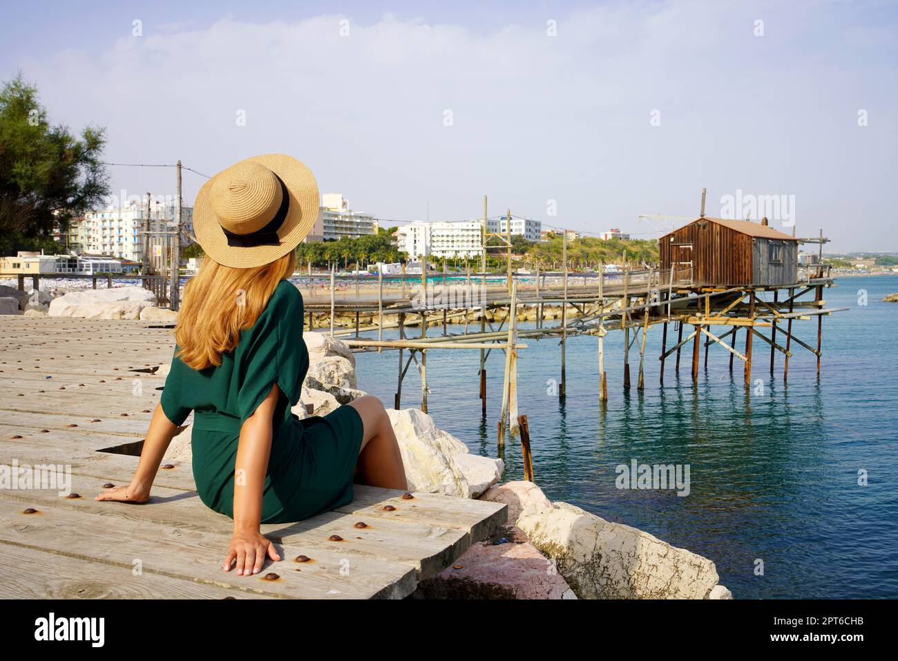 Urlaub Italy im Sommer. Rückansicht einer jungen Frau, die am Meer saß, entspannt mit der alten Trabucco-Fischmaschine an der Adria, Italien. Stockfoto