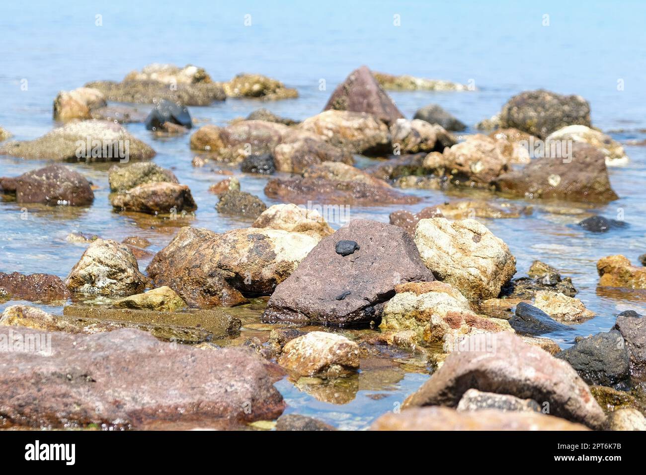 Kniestütze, Blick vom Boden aus auf die Kieselsteinfelsen am Meer. Hintergrundkonzept für den Sommerstrand am Meer. Niemand am Strand. Stockfoto