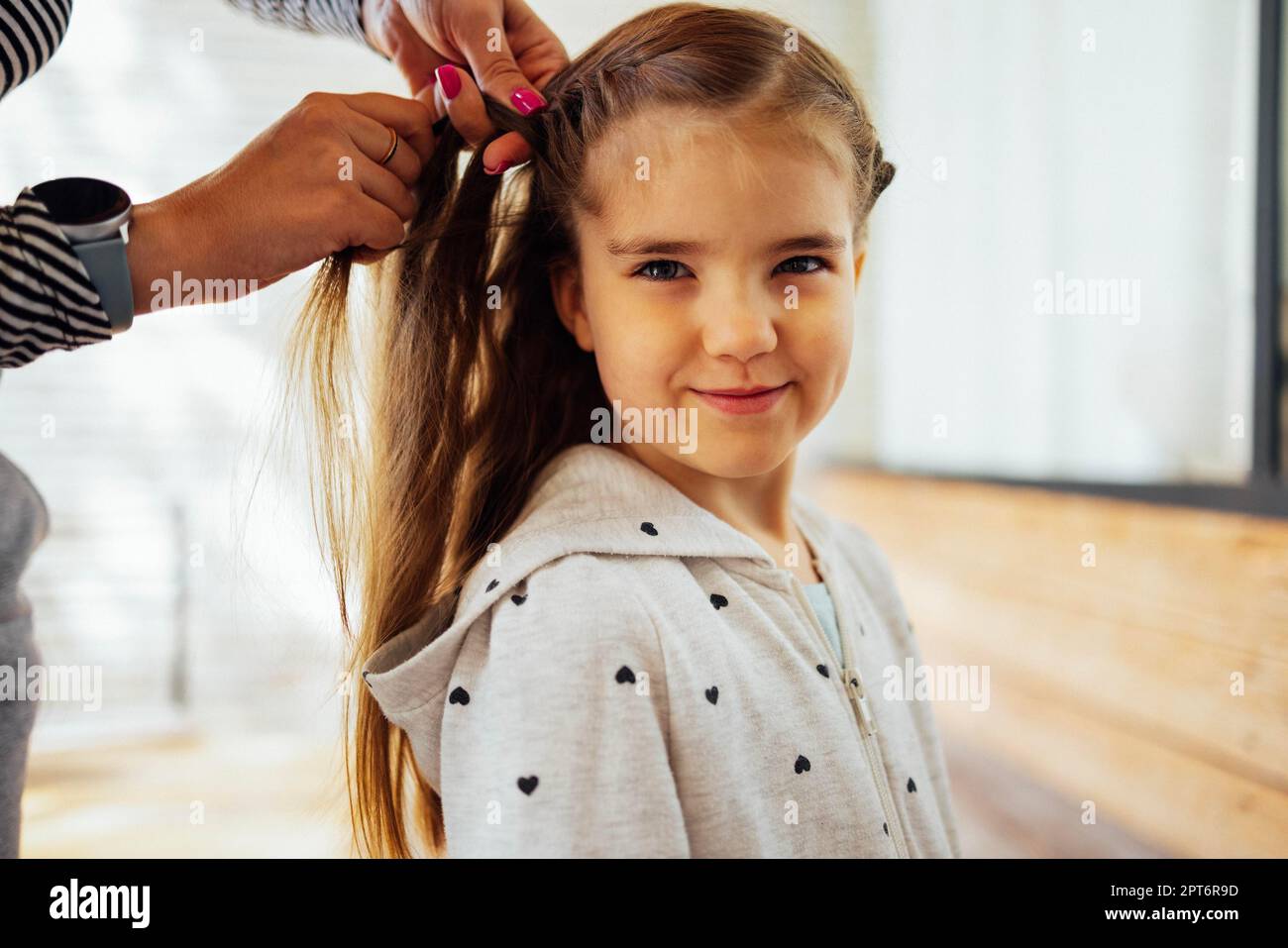 Der Friseur flechtet die Haare des Mädchens. Vorbereitung auf die Schule Stockfoto