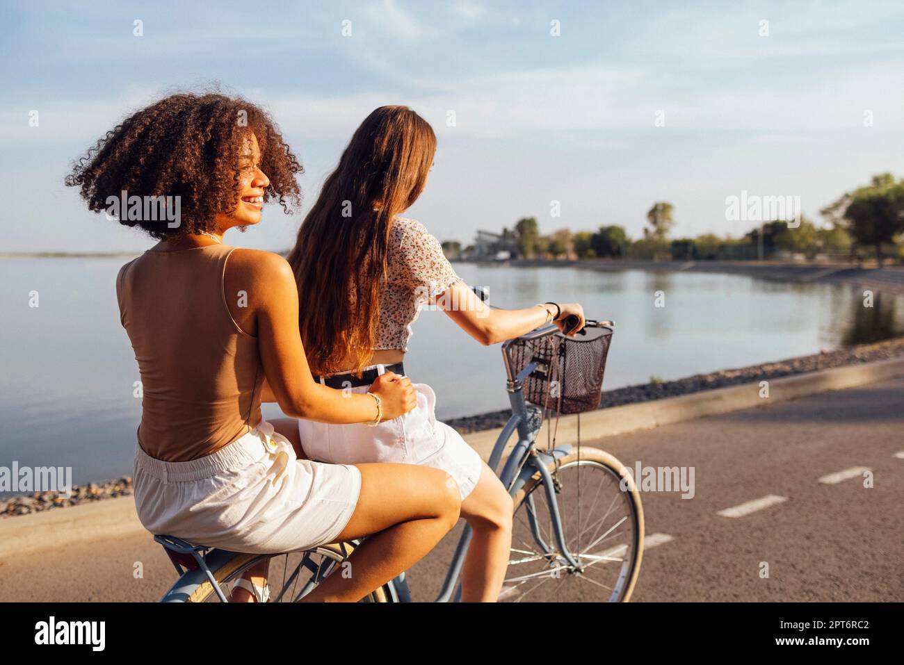 Teenager verschiedener Nationalitäten und Aussehen auf Fahrrädern fahren entlang einer Straße der Stadt. Junge und positive Mädchen lächeln zusammen. Gesunder Lebensstil Stockfoto