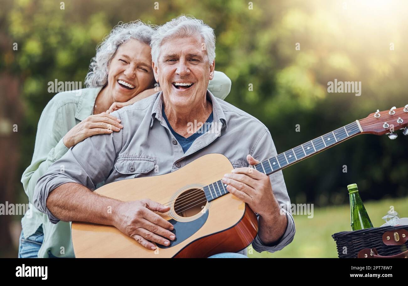 Paare, Gitarre und Picknick mit einem älteren Mann und einer älteren Frau in der Natur mit einem Lächeln und Musik zum Spaß. Glücklich, Ruhestand und Liebe mit einem älteren Mann und fee Stockfoto
