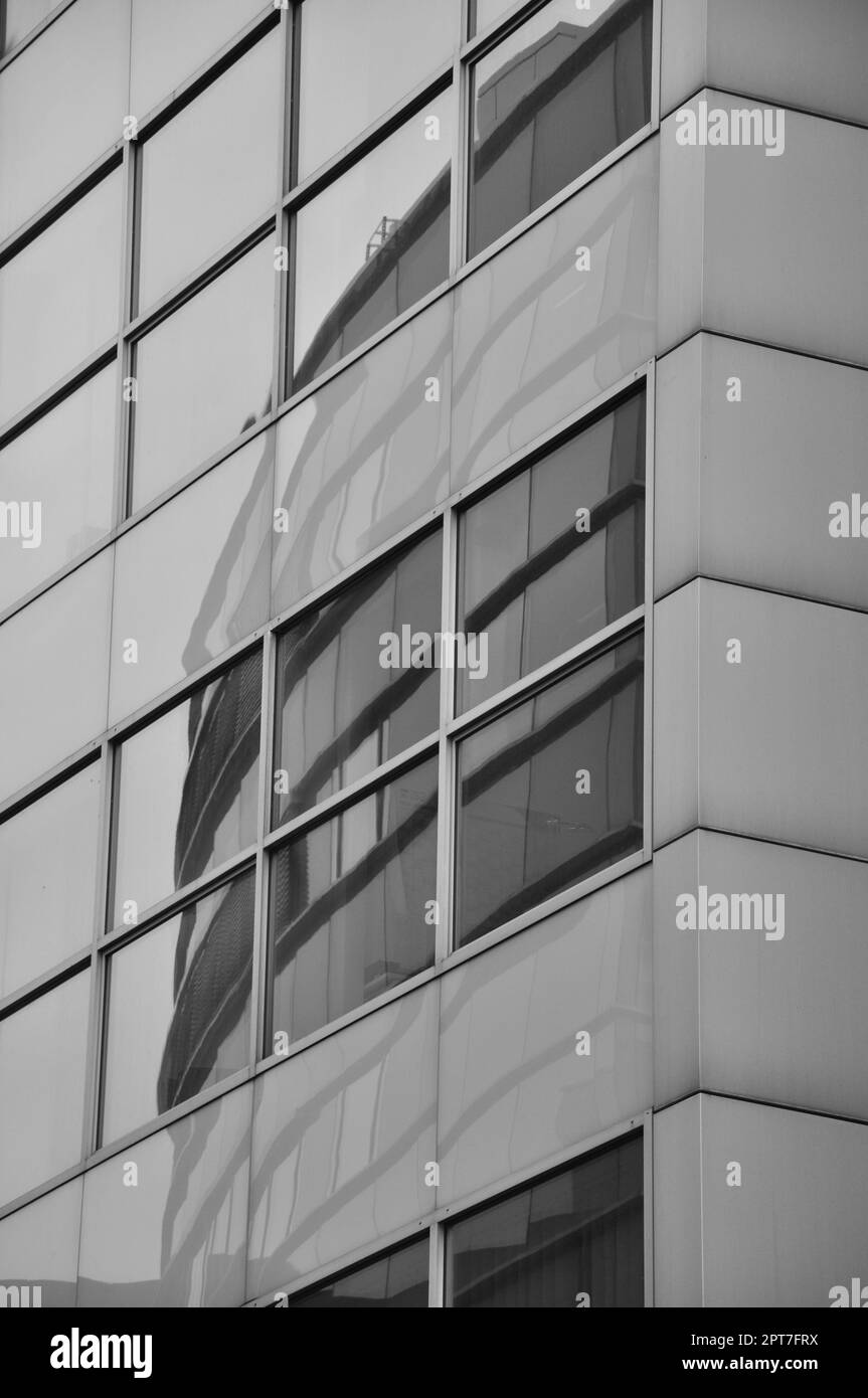 Vertikale Graustufenaufnahme von Gebäuden Reflexion in Fensterbereich in Media Harbor. Düsseldorf, Deutschland. Stockfoto