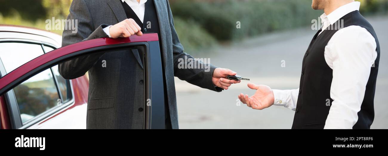 Parkservice. In Der Nähe Der Tür Stehend, Der Den Schlüssel Gibt Stockfoto