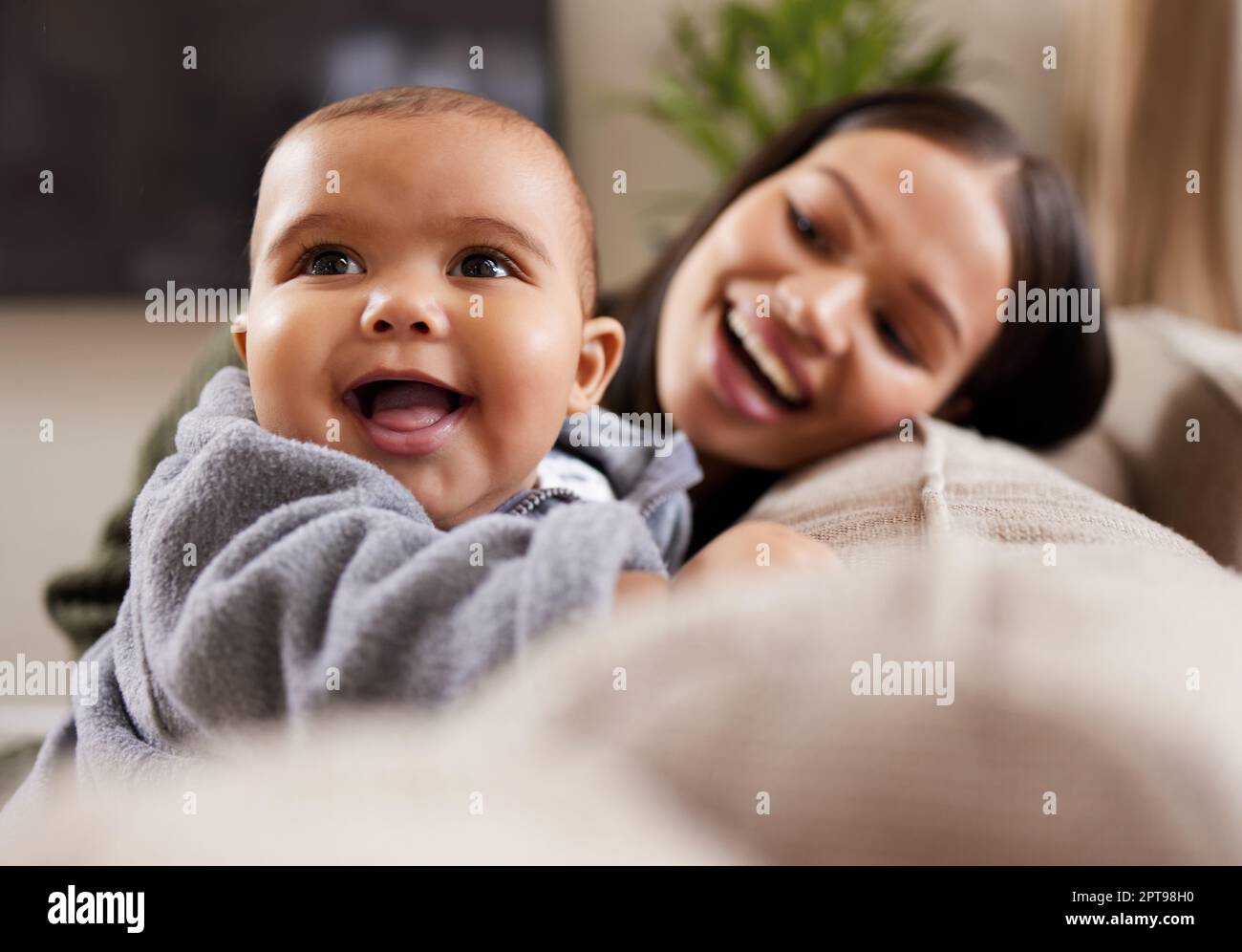 Worte können nicht die Freude eines neuen Lebens ausdrücken. Eine junge Frau, die sich zu Hause mit ihrem niedlichen Baby auf dem Sofa entspannt Stockfoto