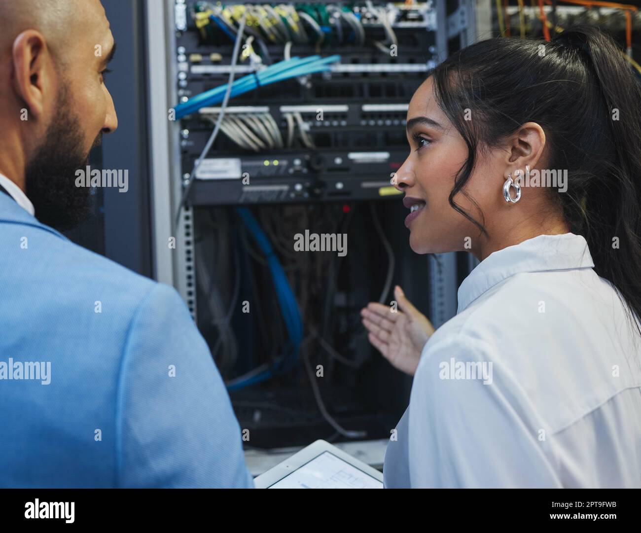 Verstehen wir uns? Zwei Mitarbeiter, die die elektronischen Geräte in einem Serverraum gemeinsam bei der Arbeit inspizieren Stockfoto
