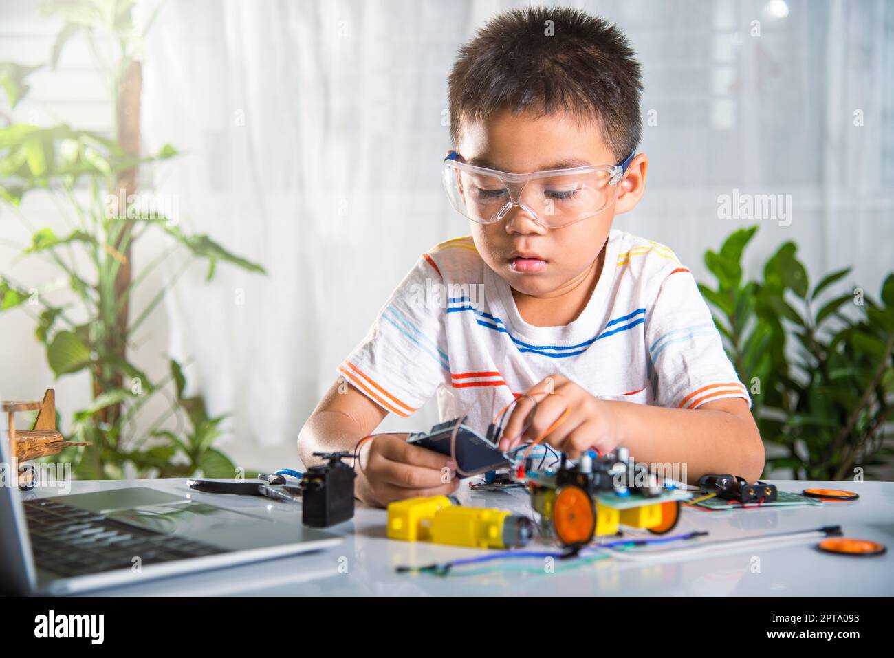 Asiatischer Junge stecken Energie-und Signalkabel an Sensor-Chip mit Arduino Roboterauto, kleines Kind aus der Ferne lernen online mit Auto-Spielzeug, DAMPF Bildung Stockfoto