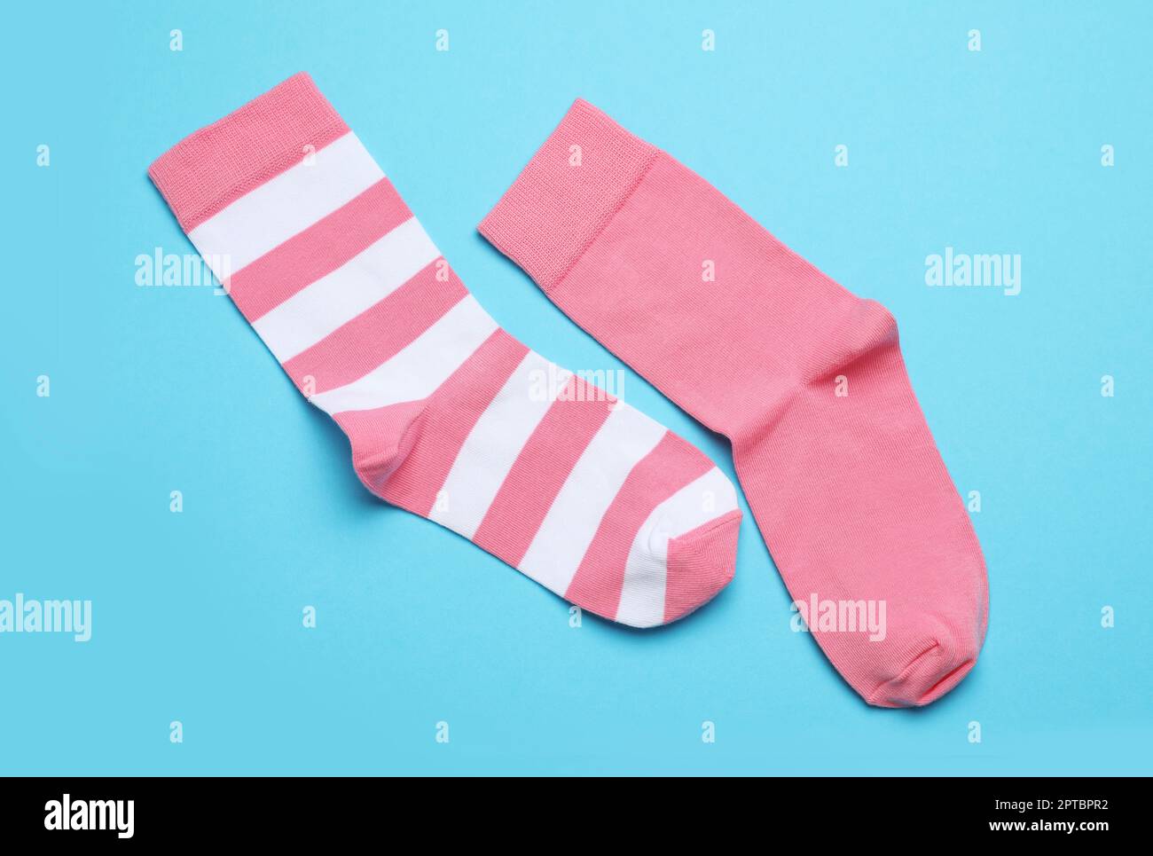 Verschiedene pinkfarbene Socken auf hellblauem Hintergrund, flach liegend Stockfoto
