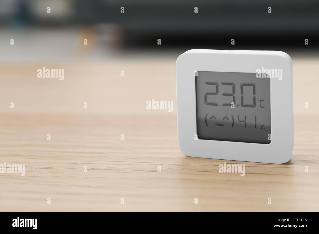 Digitales Hygrometer mit Thermometer auf Holztisch im Innenbereich. Platz für Text Stockfoto