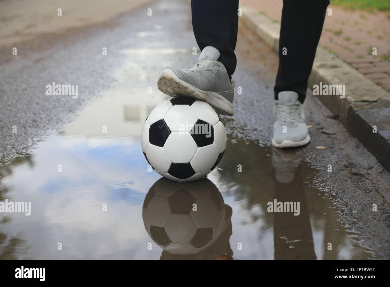 Mann mit Fußball in der Nähe der Pfütze, Nahaufnahme Stockfoto