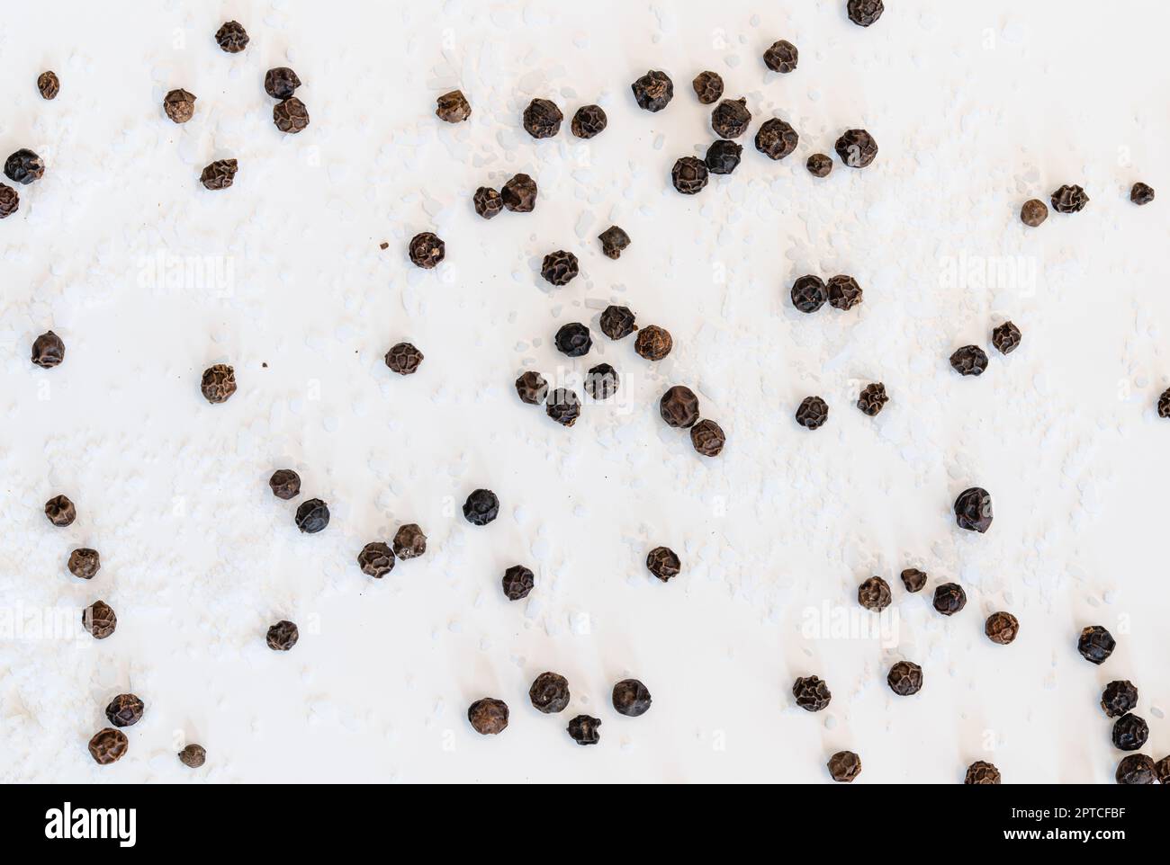 Tafelsalz und schwarze Pfefferkörner auf weißem Hintergrund Stockfoto