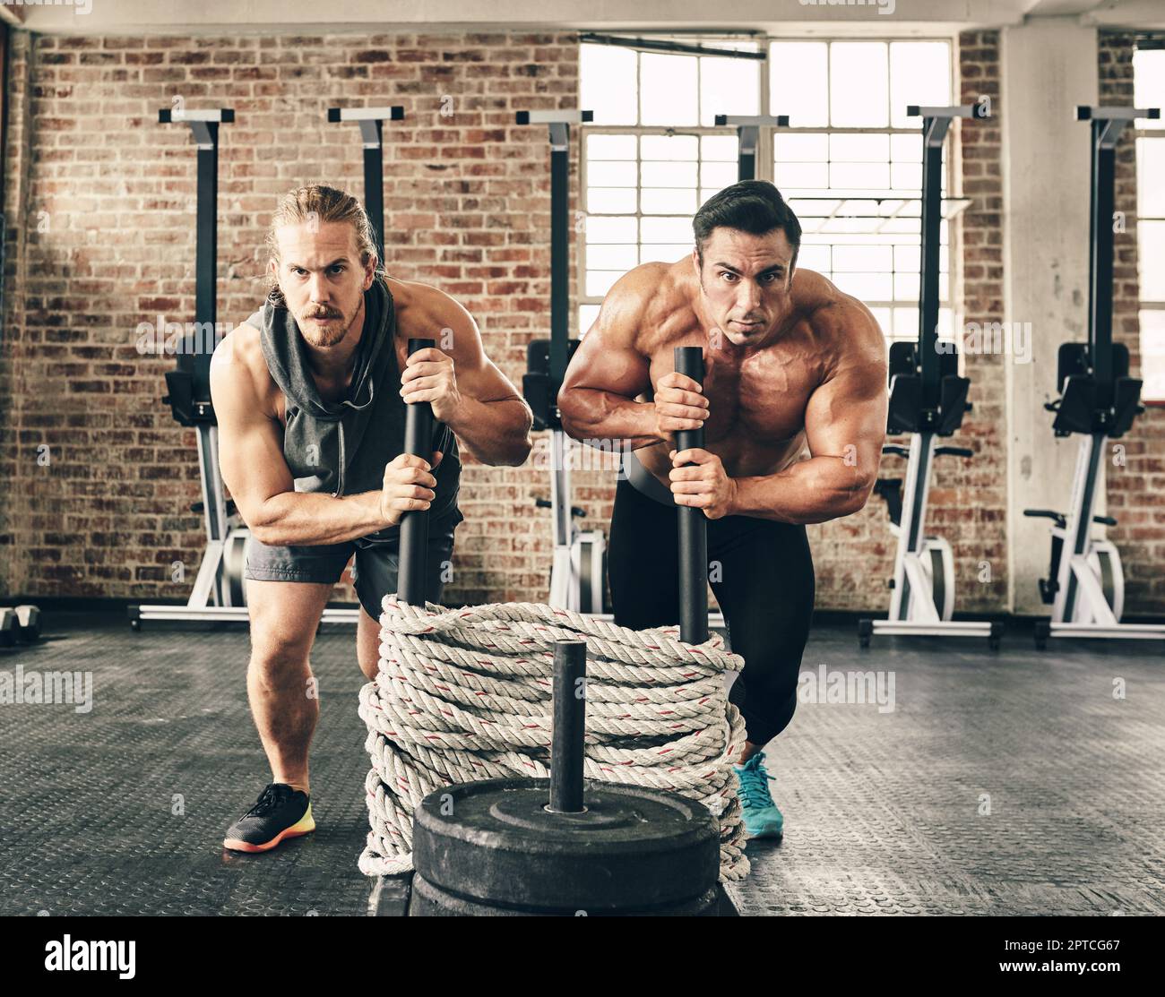 Lass uns das gemeinsam tun. Zwei fitte und entschlossene junge Männer, die Gewichte verwenden, um gemeinsam im Fitnessstudio zu trainieren Stockfoto