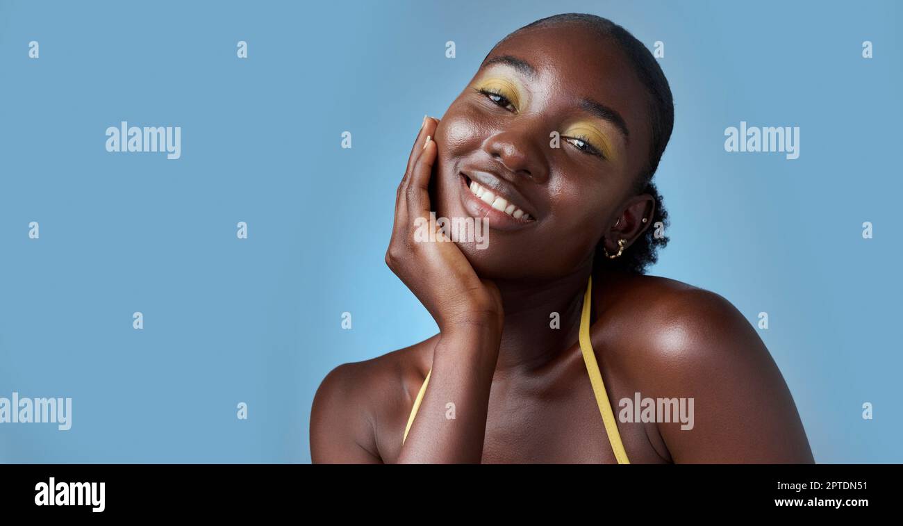 Schwarze Frau, Lächeln und Make-up in Mockup für Hautpflege Schönheit und Kosmetik vor blauem Hintergrund. Model, glücklich und Hand auf Gesicht, für die Haut Wellness und Stockfoto