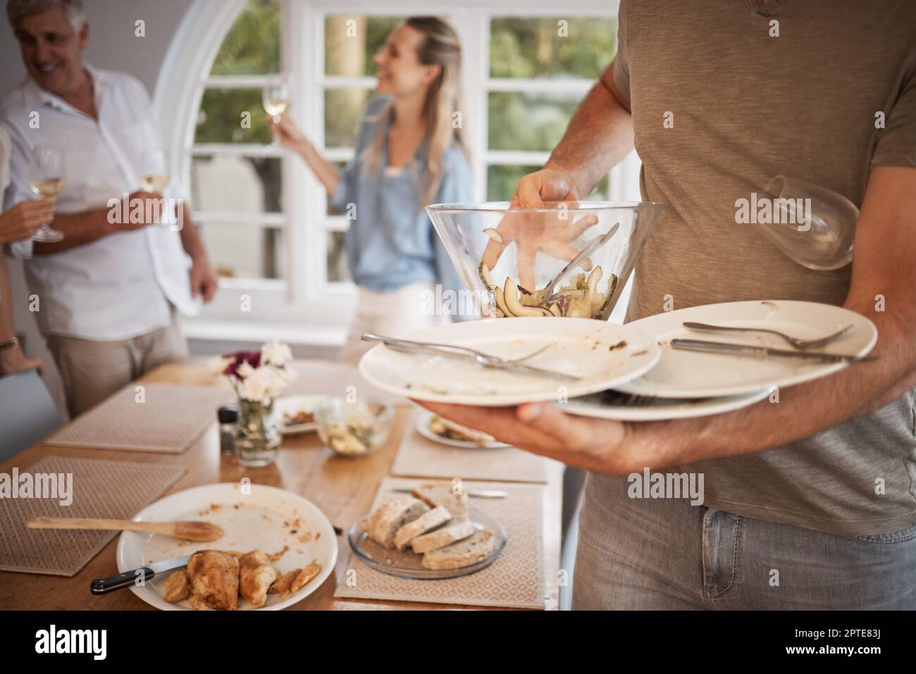 Mittagessen, Familie und Mann räumen nach dem Essen vom Tisch das Geschirr  ab. Nach dem Mittagessen mit der Familie aufräumen, wegpacken und Teller  vom Esstisch abräumen Stockfotografie - Alamy