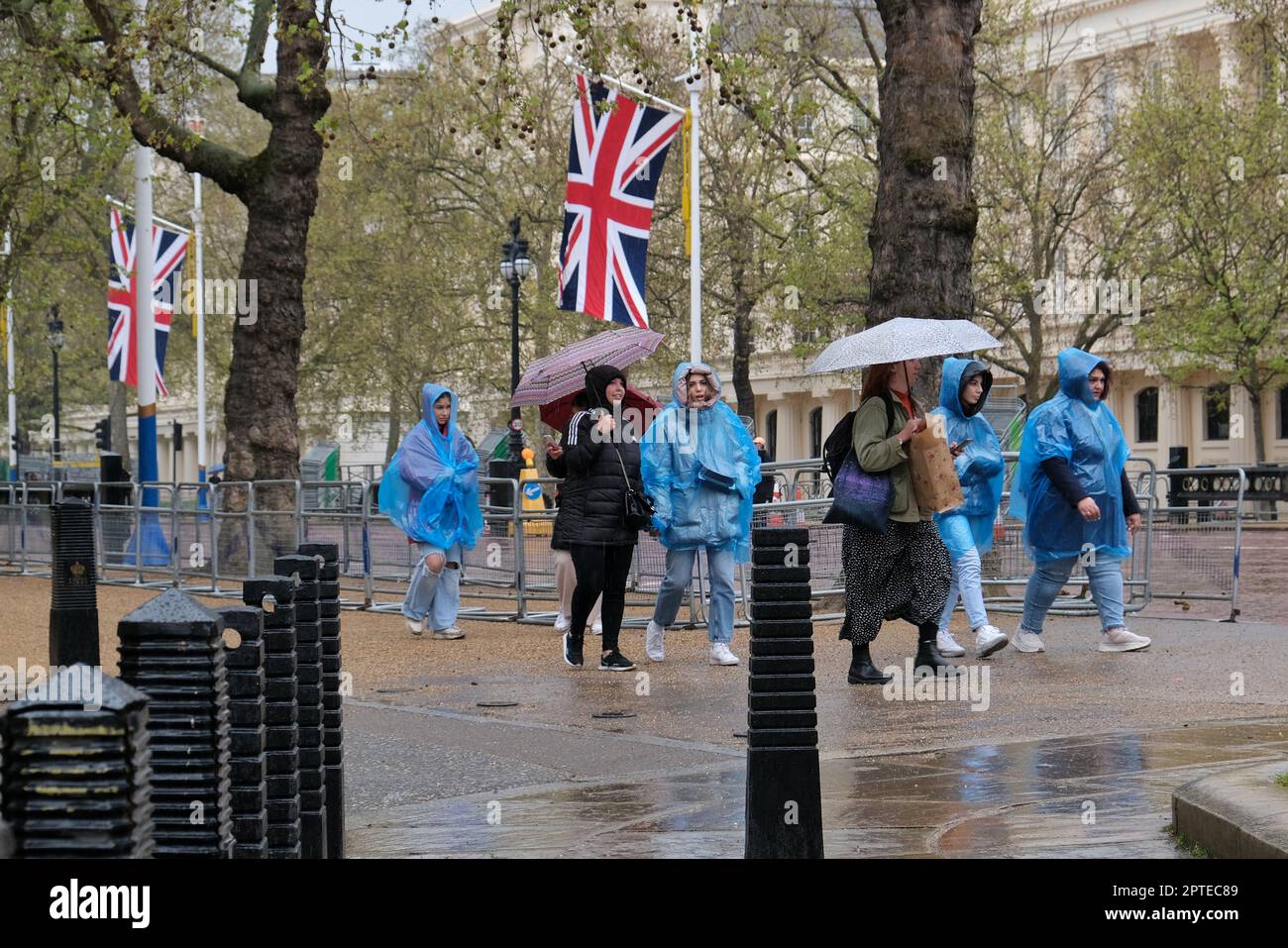 London, Großbritannien. An einem nassen Frühlingstag benutzen Touristen in der Mall Regenschirme und blaue Einwegponchos. Stockfoto