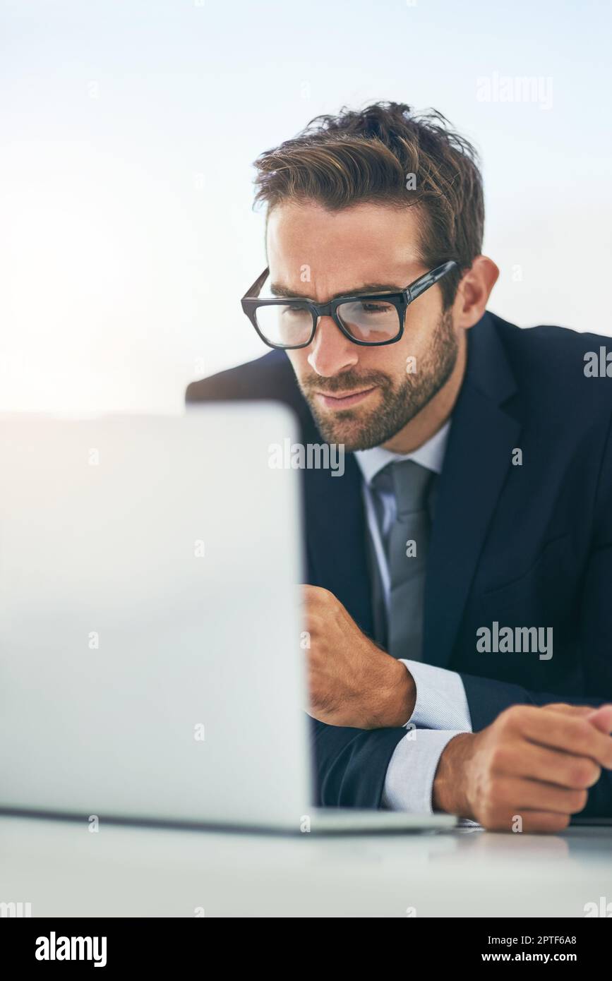 Kein Hindernis ist zu schwer für ihn anzugehen. Ein attraktiver junger Geschäftsmann, der in einem Büro an einem Laptop arbeitet Stockfoto