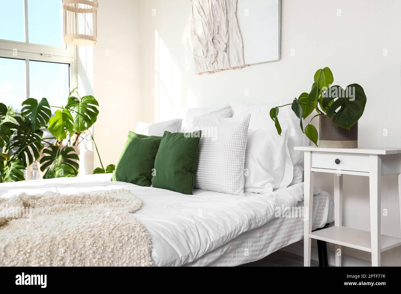 Helles Schlafzimmer mit Monstera-Zimmerpflanze und Bett Stockfotografie -  Alamy