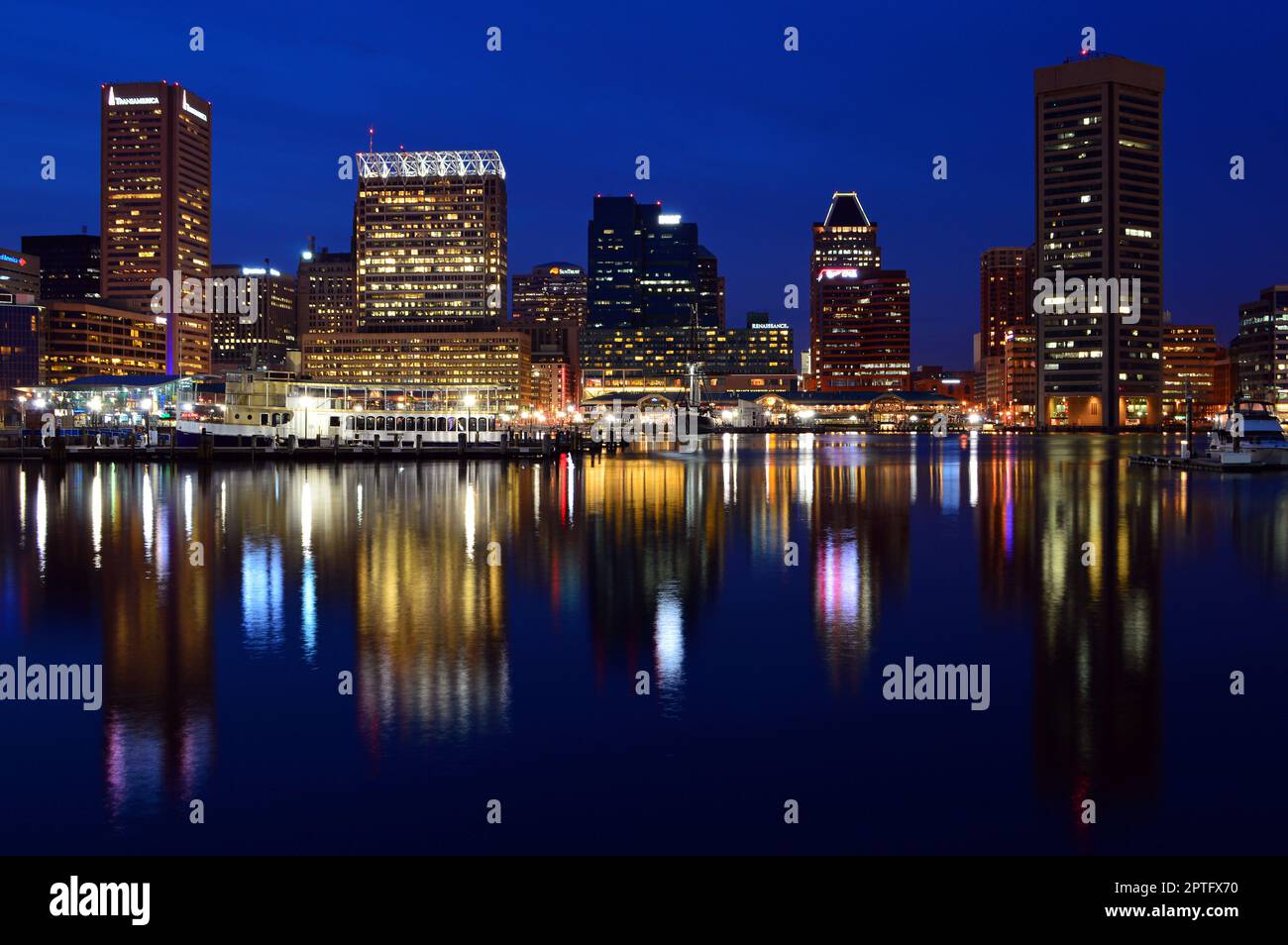 Die Lichter der Skyline von Baltimore sind beleuchtet und spiegeln sich im Wasser von Inner Harbor Stockfoto