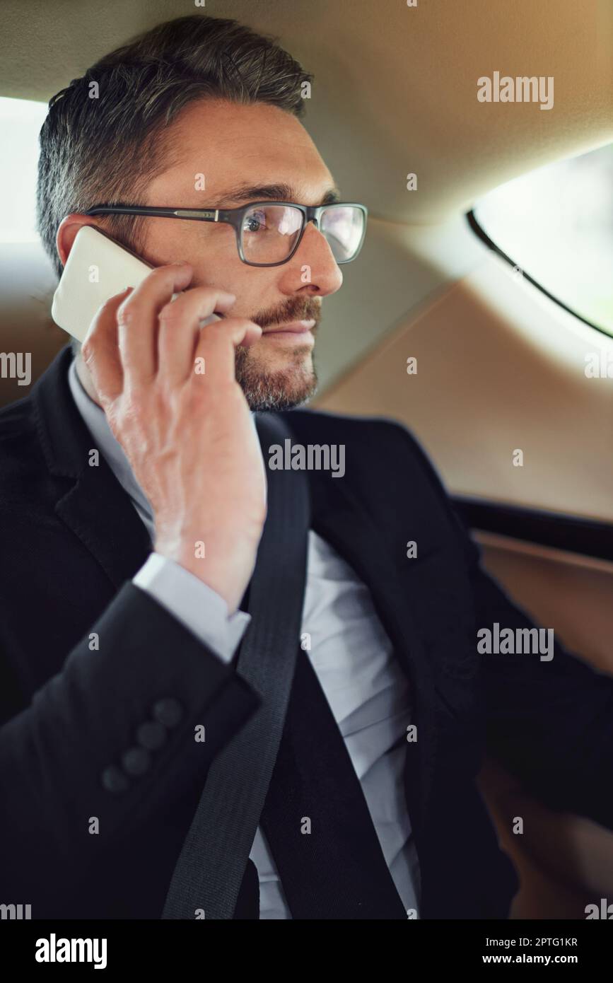 Sagen Sie heute alle meine Meetings ab. Ein Geschäftsmann, der sein Handy benutzt, während er auf dem Rücksitz eines Autos sitzt Stockfoto