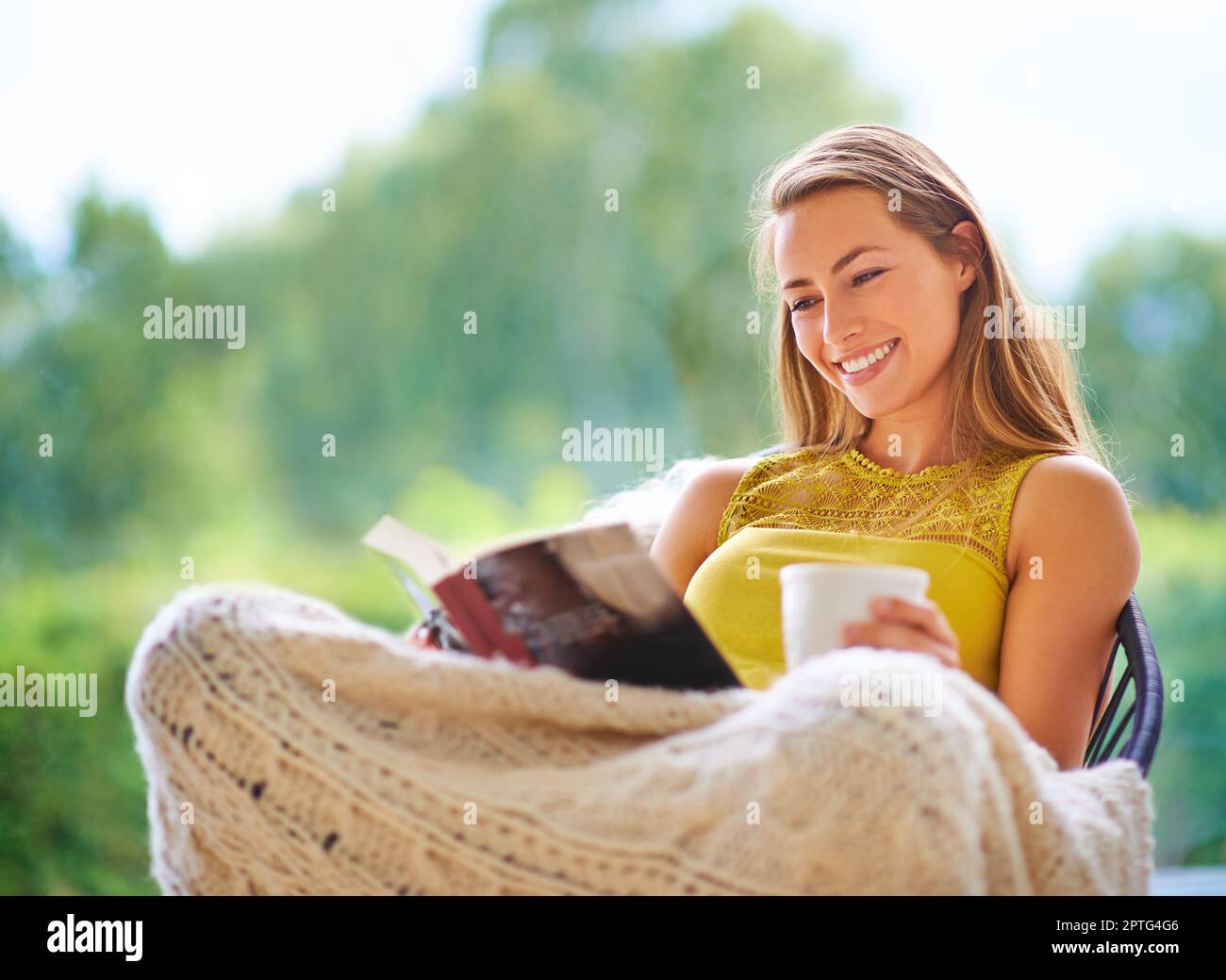 Mit Kaffee wird alles besser. Eine junge Frau, die zu Hause ein Buch liest Stockfoto