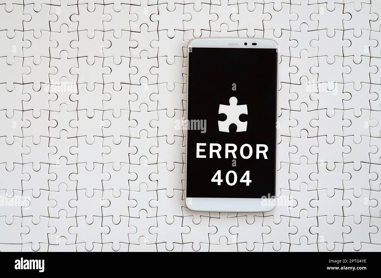 Eine moderne grosse Smartphone mit Touchscreen liegt auf einem weißen Puzzle im zusammengebauten Zustand mit Inschrift. Fehler 404 Stockfoto