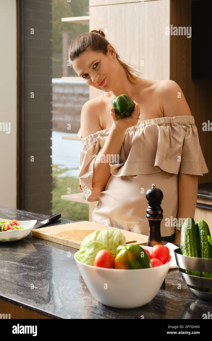 Eine Schwangerin hält frischen grünen Paprika in der Hand Stockfoto