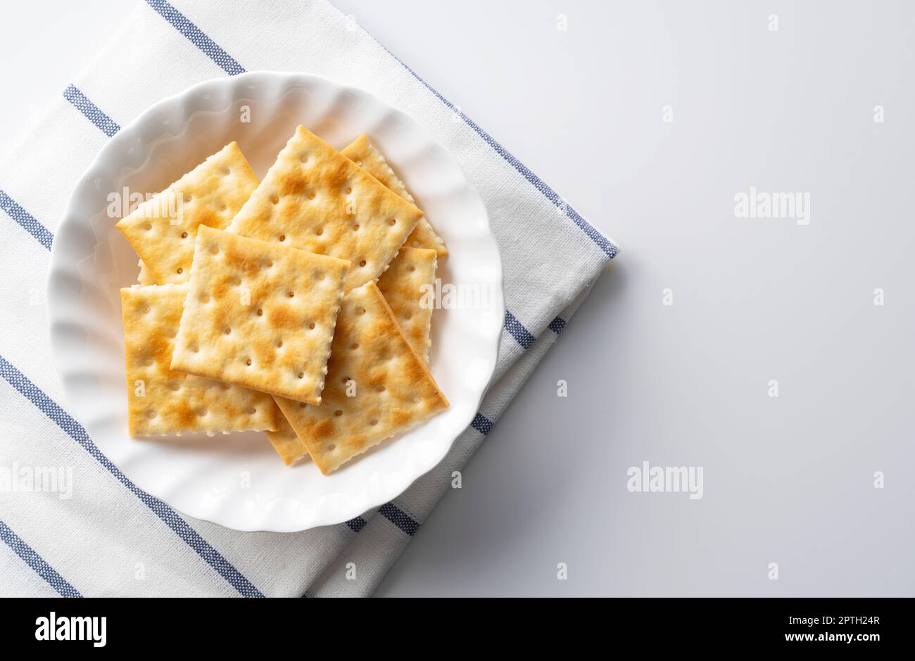 Viele Cracker auf einer Platte, die auf einem weißen Hintergrund mit Platz platziert ist. Blick von direkt oben. Stockfoto