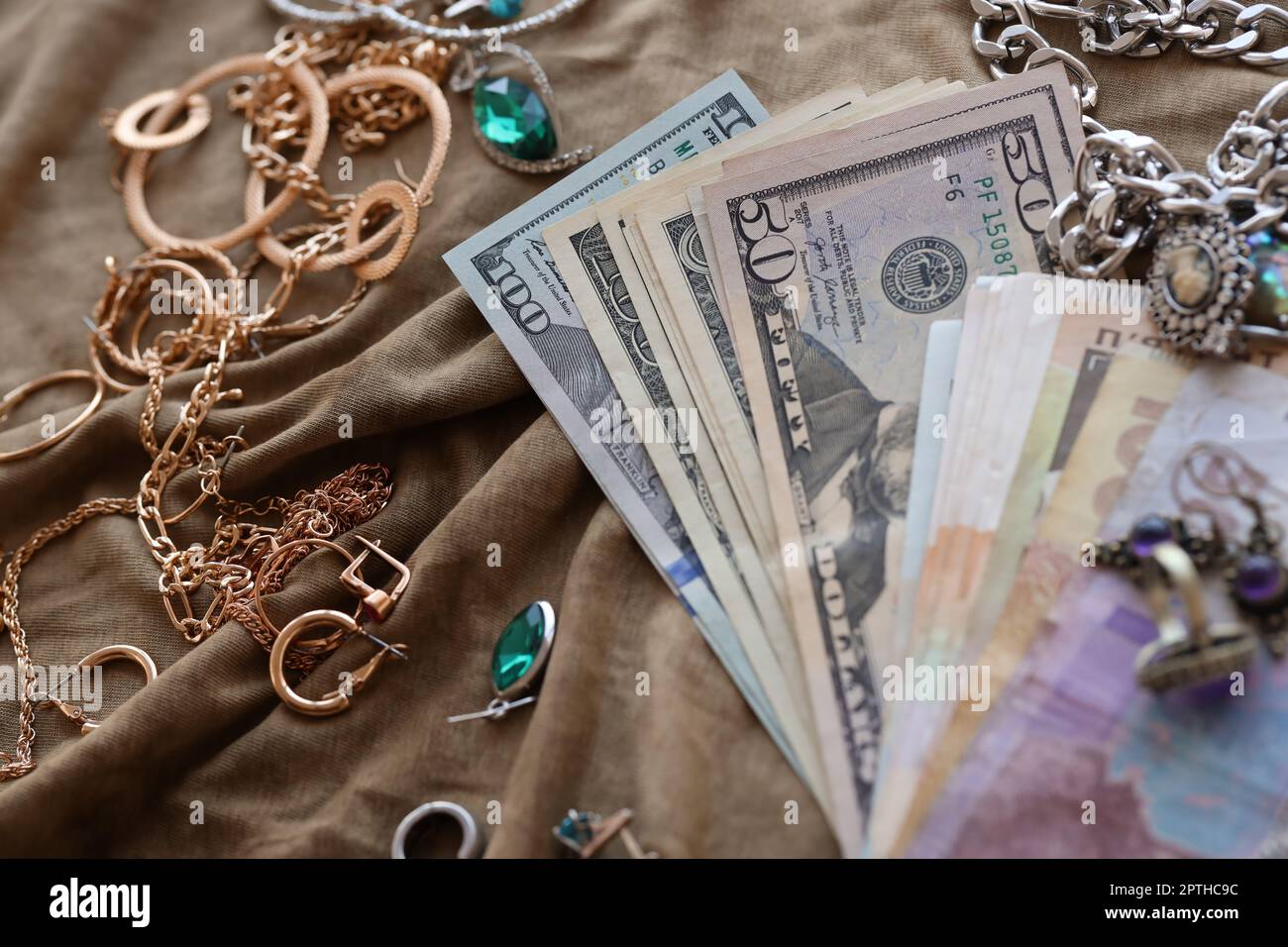 Haufen gestohlener Schmuck und Geld auf Militäruniform Stoff. Plünderung durch russische Soldaten in ukrainischen Städten während des russischen Angriffs auf U Stockfoto