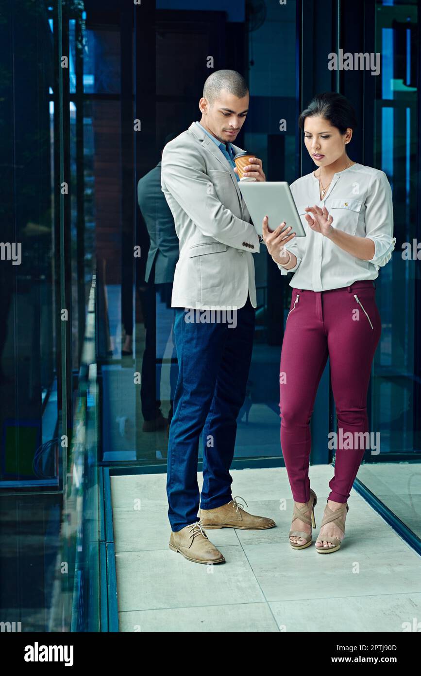 Die Freigabe von Office-Updates war noch nie so einfach. Zwei junge Kollegen, die zusammen ein digitales Tablet verwenden. Stockfoto