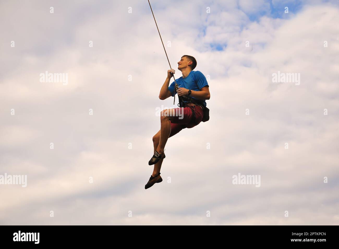 Kletterer hängt am Seil am Himmelshintergrund Stockfoto