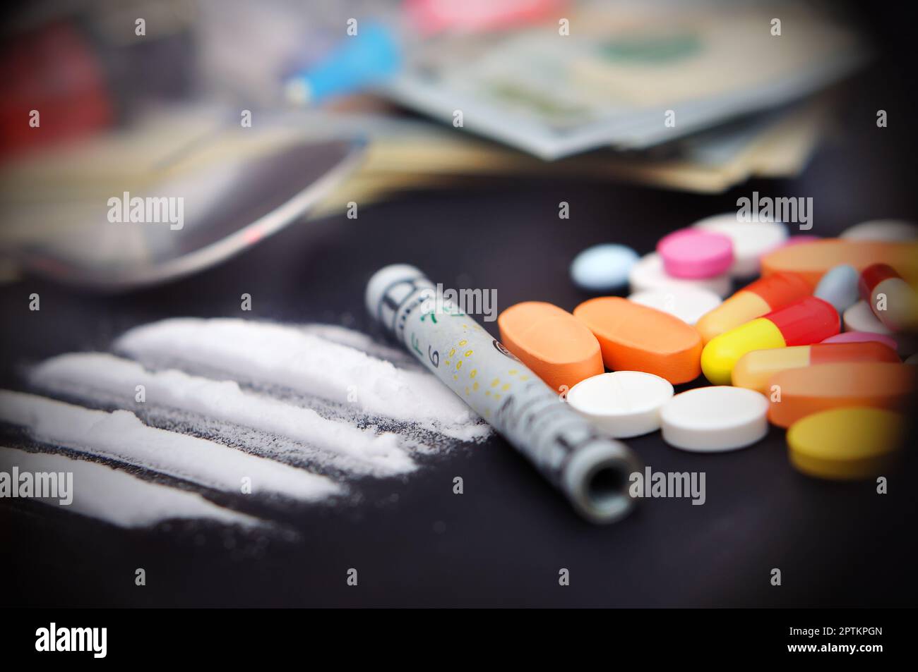 Kokainlinien neben einem eingepackten Dollarschein und Drogen-Pillen Stockfoto