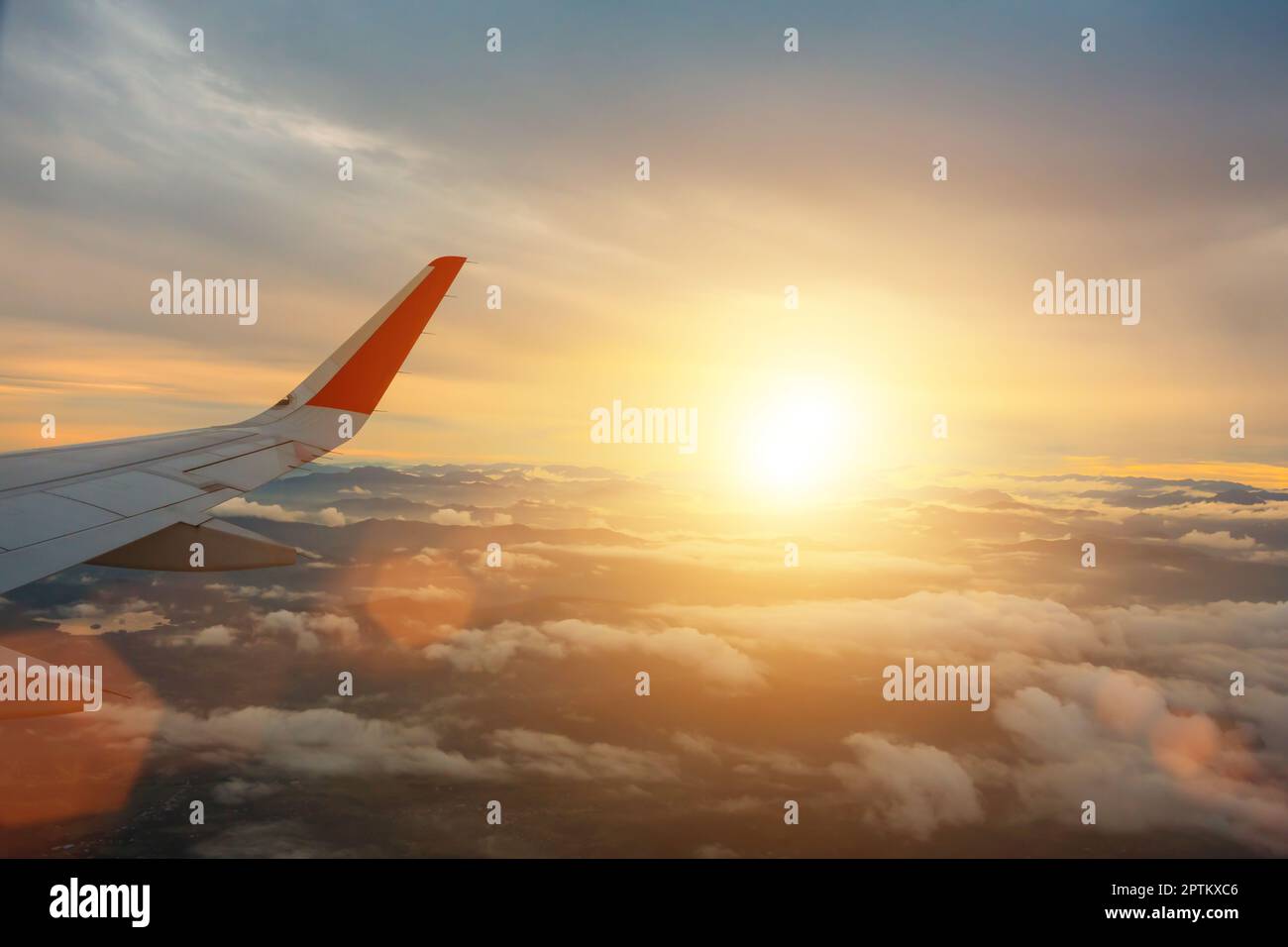 Flügel eines Flugzeugs, das über dem Berg mit Sonnenuntergang fliegt. Stockfoto