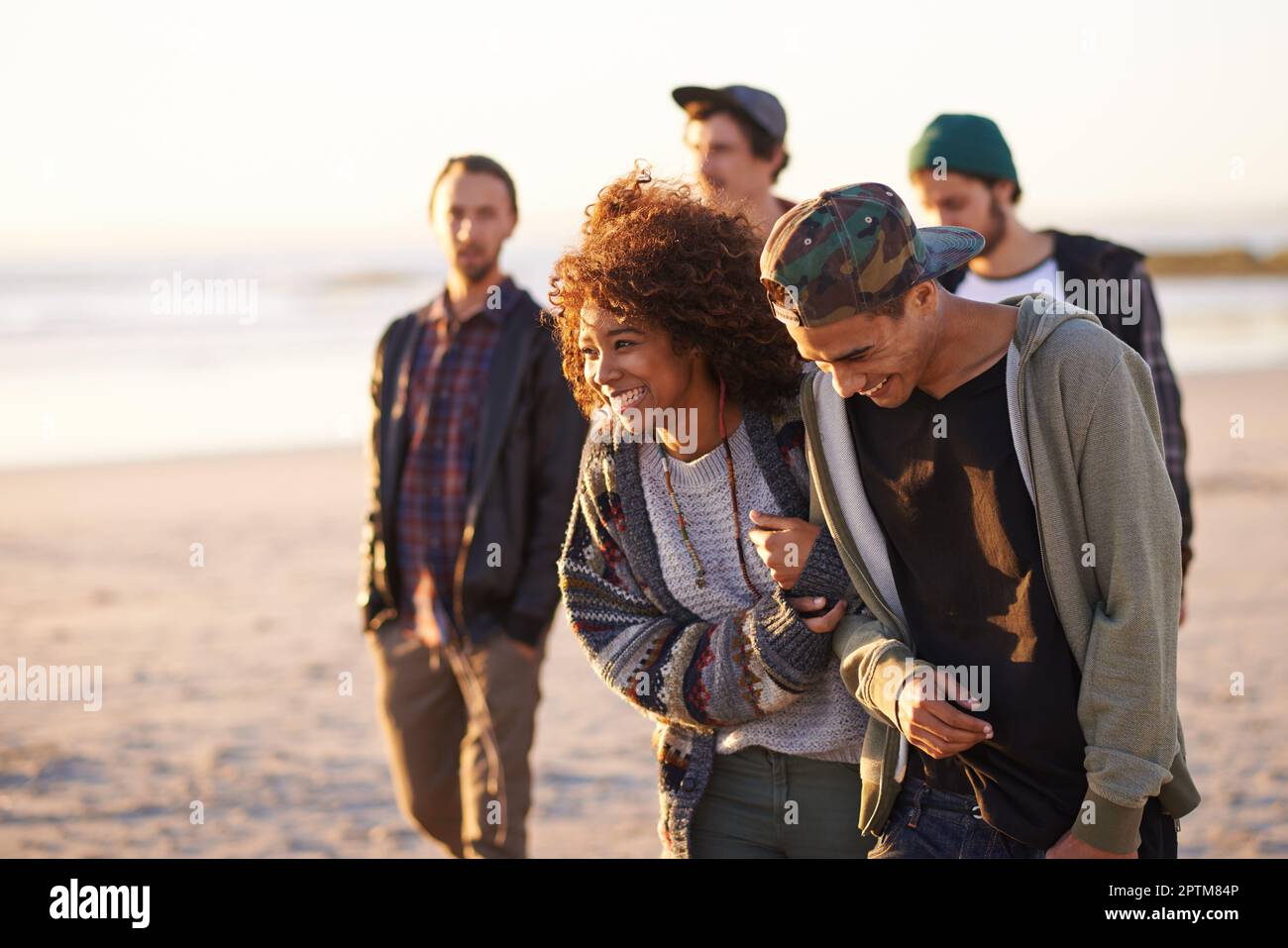 Sie lassen alle stehen und starren. Eine Gruppe von Freunden, die bei Sonnenuntergang am Strand spazieren Stockfoto