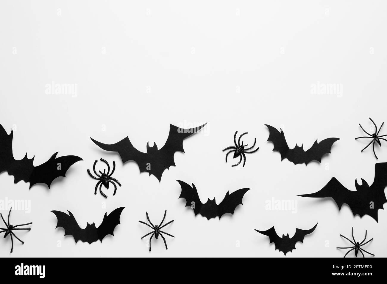 Flache Laienzusammensetzung mit Papierschlägern und Spinnen auf weißem Hintergrund, Platz für Text. Halloween-Feier Stockfoto