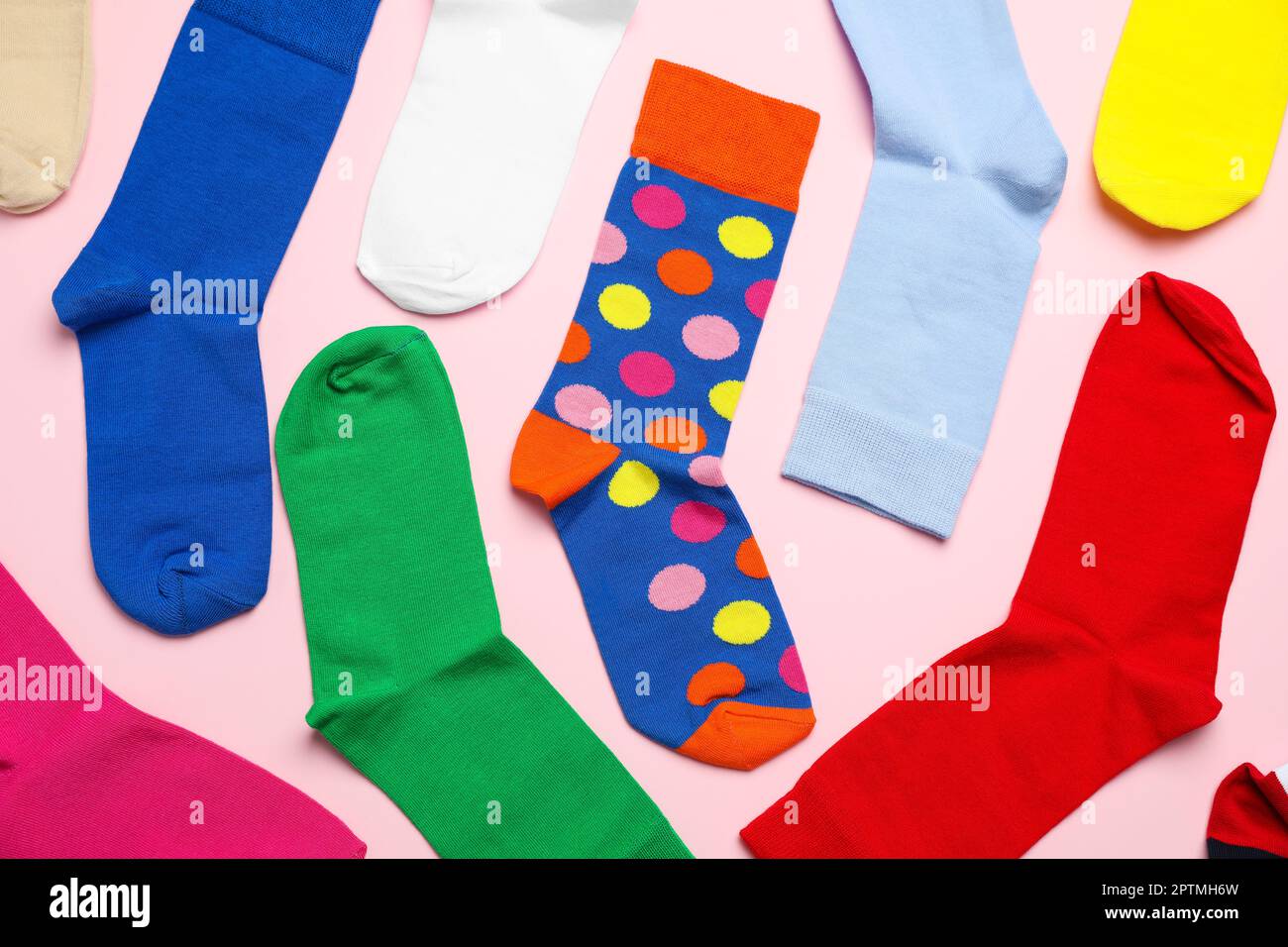 Viele verschiedene bunte Socken auf hellrosa Hintergrund, flach liegend Stockfoto