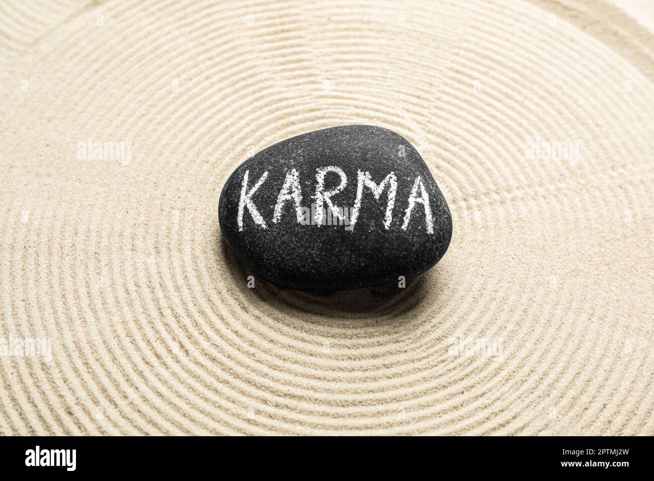 Stein mit dem Wort Karma und Kreise auf Sand, Draufsicht Stockfoto